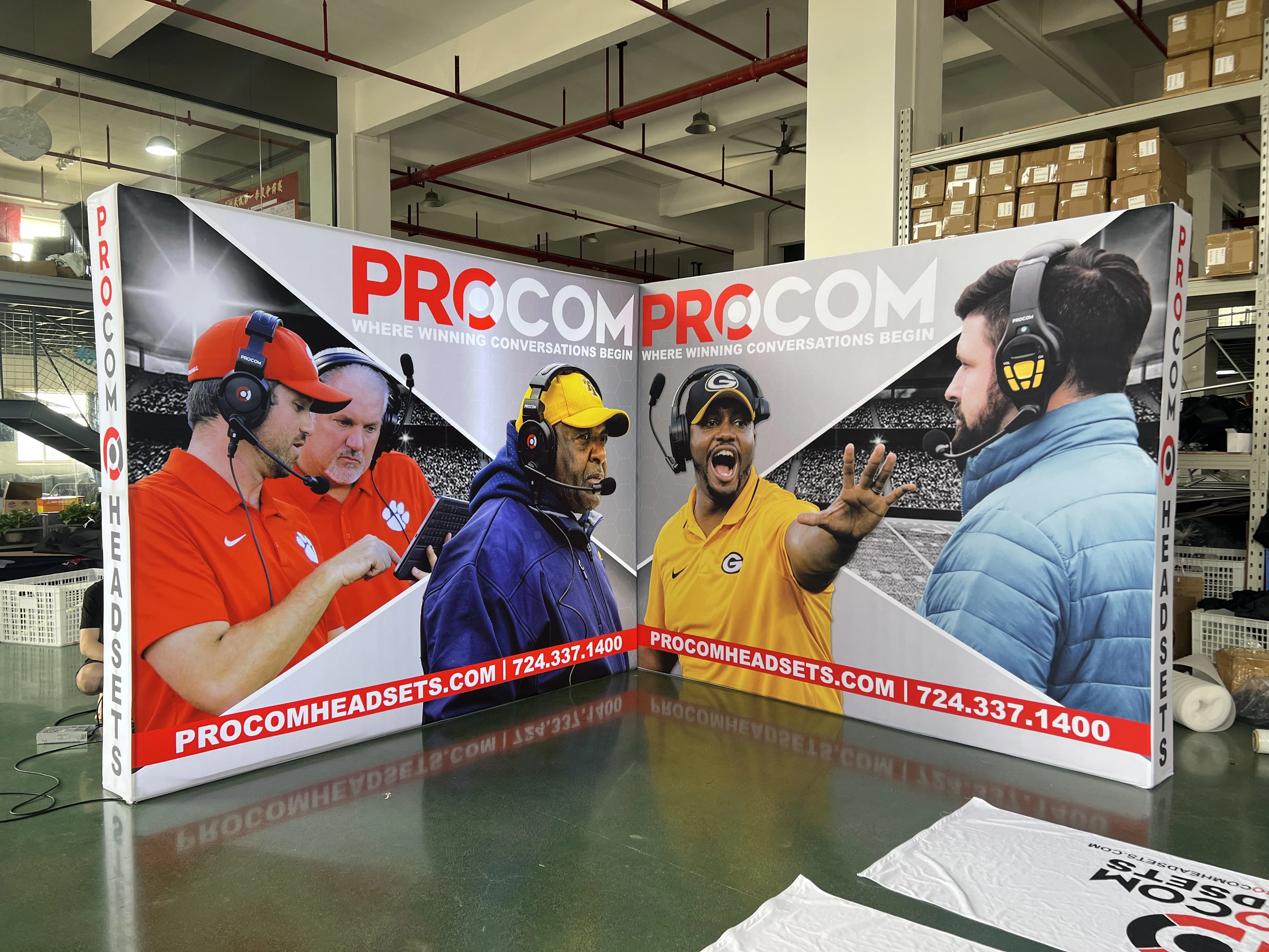 L-shaped SEG fabric lightbox display featuring high-resolution graphics of football coaches using headsets.