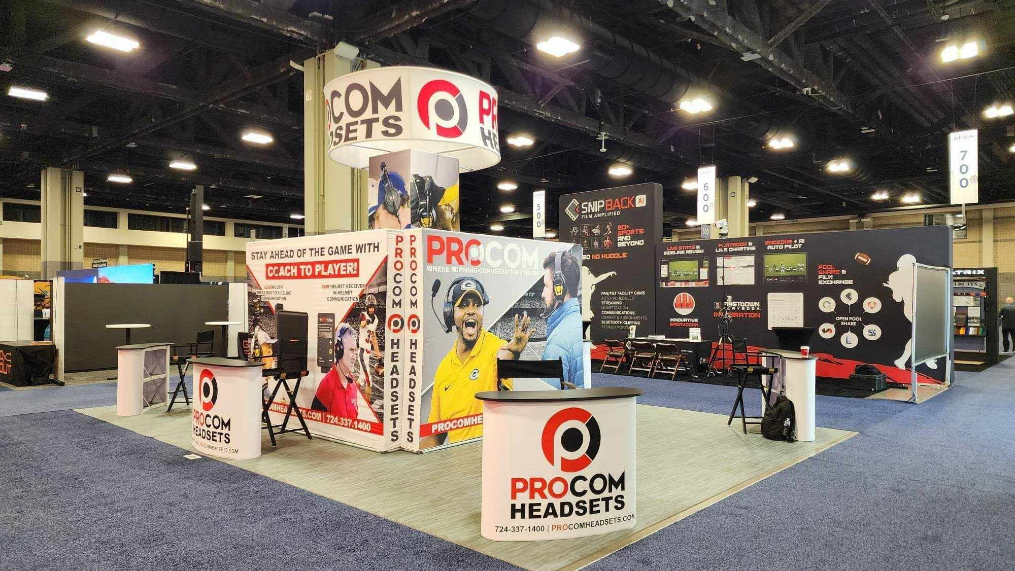 ProCom 20x20 trade show booth featuring a circular hanging banner and backlit SEG fabric walls.